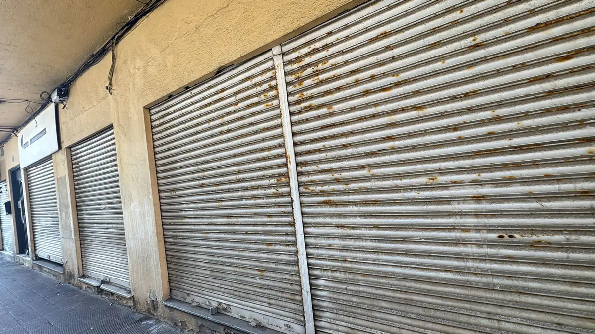 Fila de cierres metálicos antiguos en la calle, con la chapa manchada y con óxido