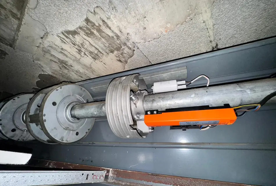 Motor montado sobre el eje de una persiana metálica, con el cableado ya conectado